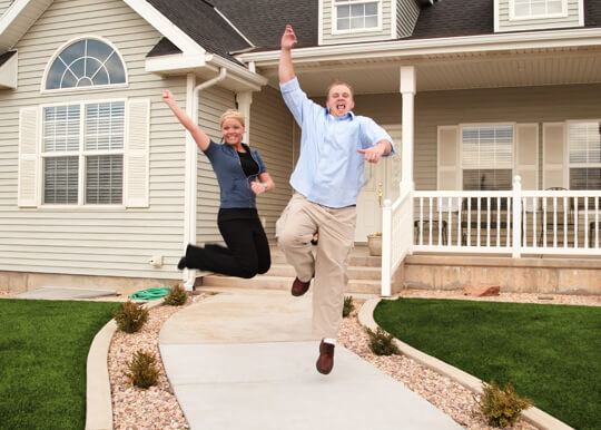 No Appraisal Loan: Happy couple leaping for joy in front of their new nome.