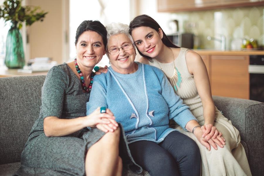 Three generations of women - a grandmother, her daughter and her granddaughter pose for a portrait.