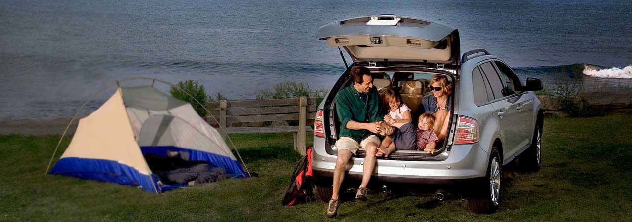 Auto Loans: Family sitting in the back of their hatchback car as they camp near the ocean.