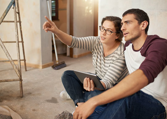 young couple sitting on floor talking about remodeling house
