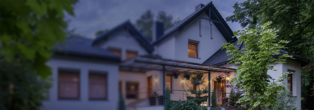 Suburban home exterior at dusk with its lights on.