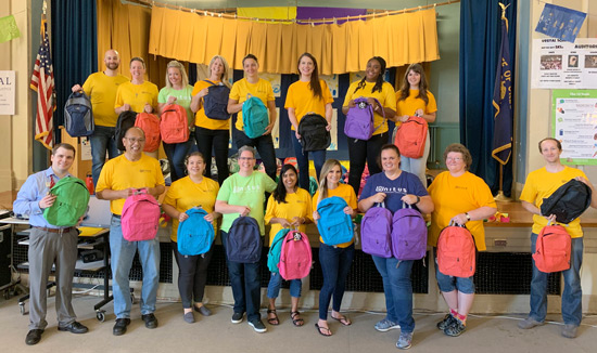 Unitus employees packing backpacks with schoolhouse supplies
