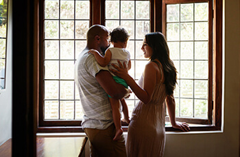 young family standing by window