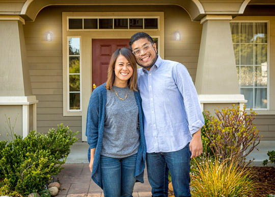 young couple in front of new house