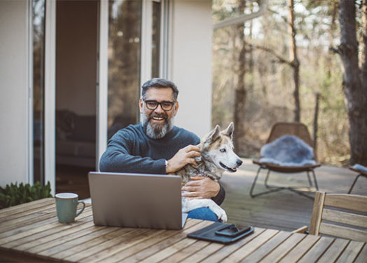 hombre sonriente videochat en el patio trasero sosteniendo a su perro