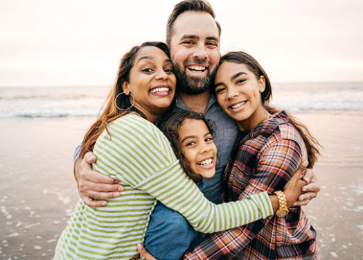 padres sonrientes con dos niños en la playa