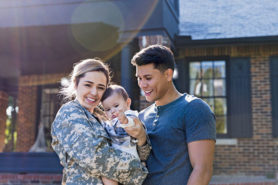 Young military family in front of new home.