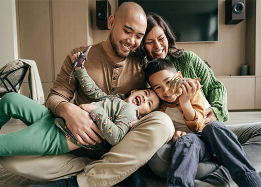 joven familia de 4 personas acurrucada en el sofá