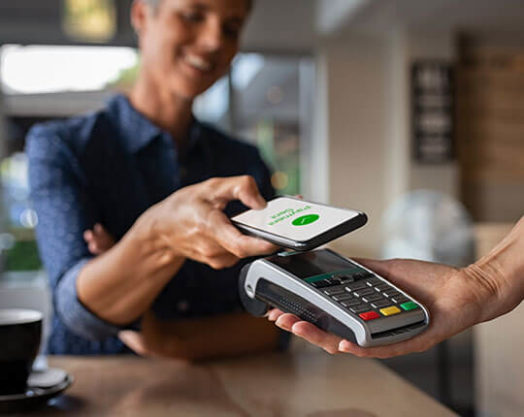 Woman paying bill through smartphone using NFC technology in a restaurant.