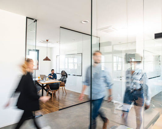 Blurred motion of energetic businesspeople on the go and project team members discussing ideas in a conference room.