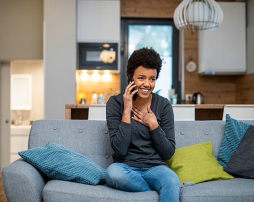 woman making a phone call and sitting on the sofa looking relieved