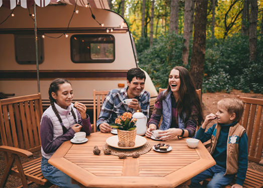 Familia feliz de acampada relajándose en el bosque otoñal.