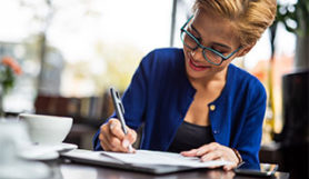 Mujer joven escribiendo un cheque en una cafetería.