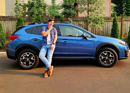 happy looking young man standing next to car