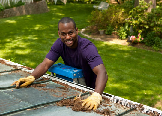 man on ladder cleaning gutters