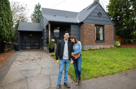 Gen X couple standing in front of new home