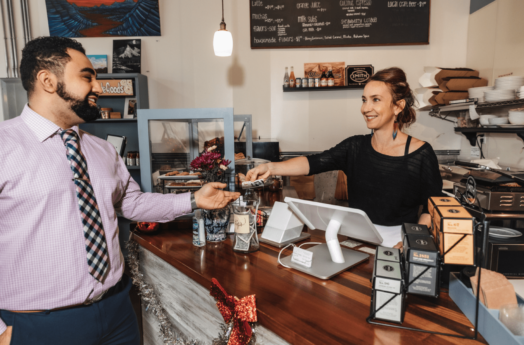 member handing credit card to small business owner