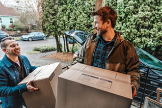 two men carrying moving boxes into house