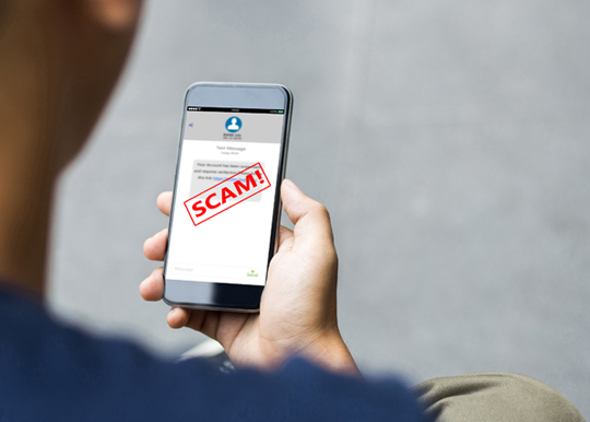 man holding mobile phone with scam text message on the screen